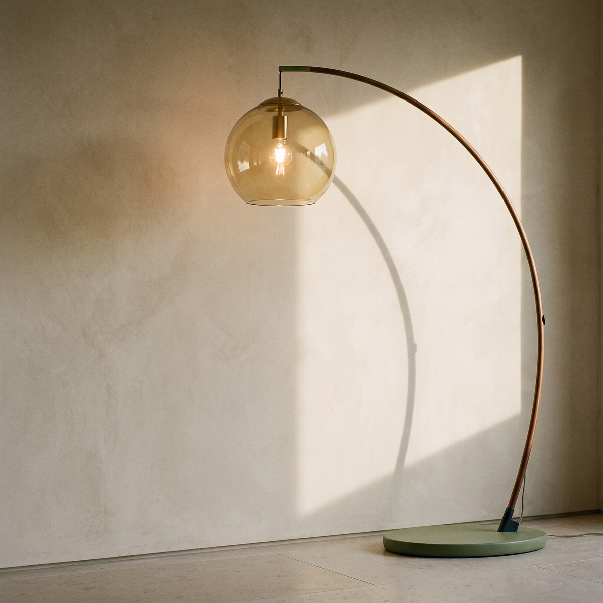 Walnut arc floor lamp with an amber glass globe shade on a sage disc base, in late afternoon light