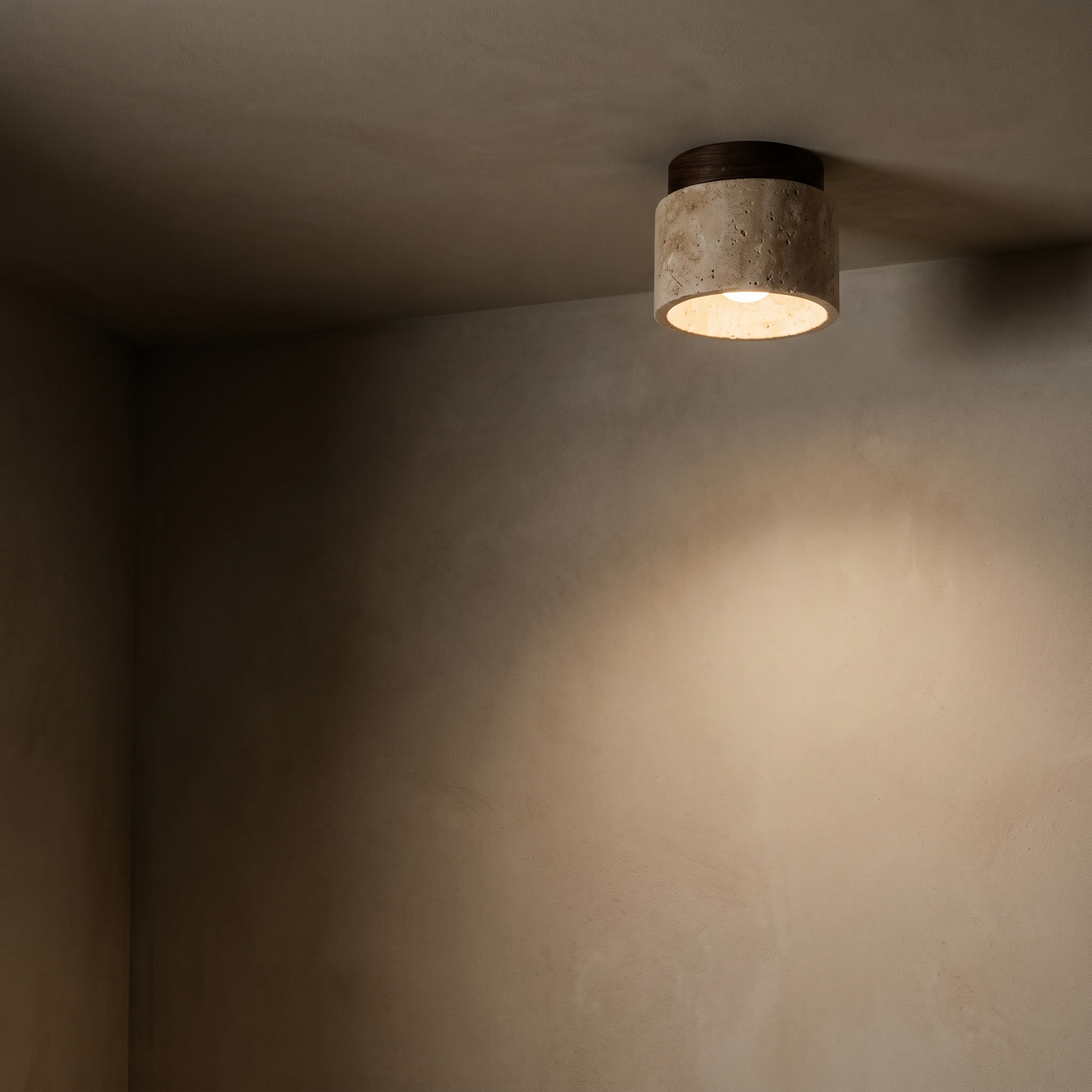 Travertine ceiling downlight washing warm light down a bone plaster wall at night